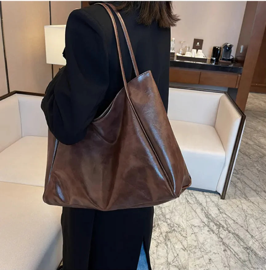 Person holding a brown leather bag in an indoor setting